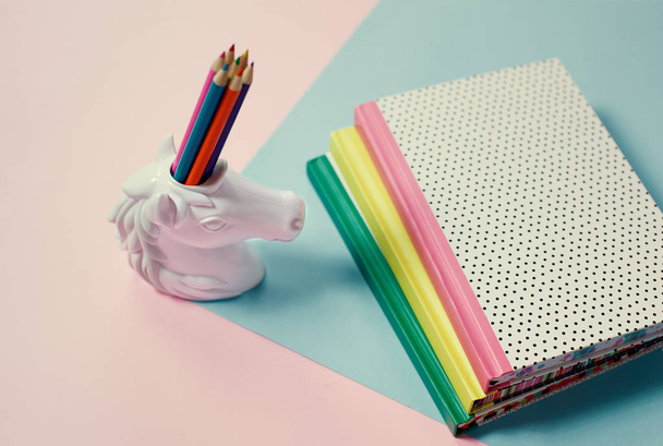 stationery items pop art pastel background unicorn pencil holder and note-books - Foto, Imagen