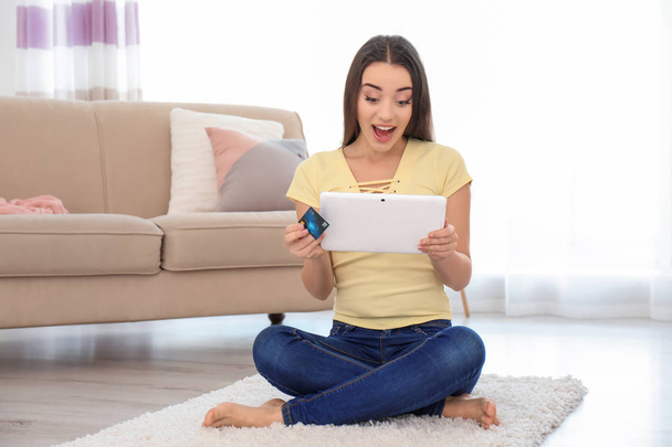 Young woman shopping online with credit card and tablet at home - Foto, imagen