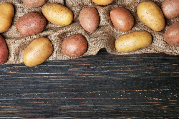 Fresh raw potatoes on wooden background, top view - Foto, afbeelding