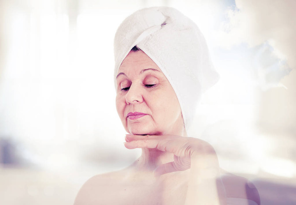 Spa and beauty concept. Aged good looking woman with white towel on her head - Foto, Imagem