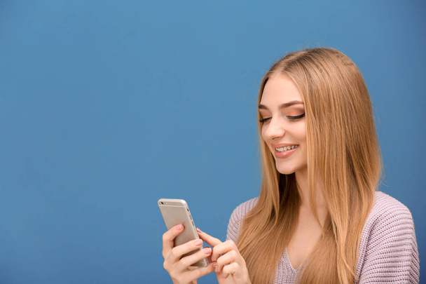 Fiatal nő, mobiltelefon színes háttérrel - Fotó, kép