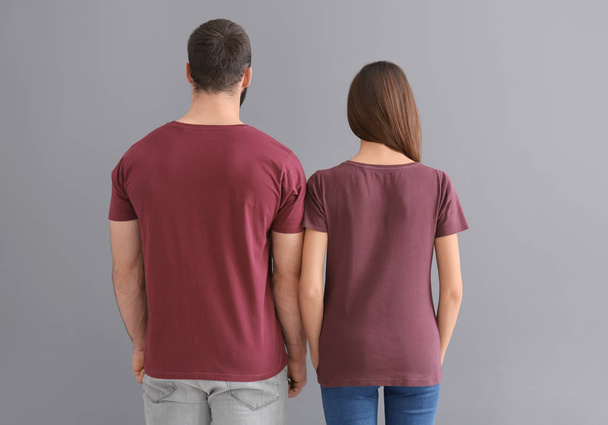 Nuori mies ja nainen tyylikkäissä t-paidoissa harmaalla taustalla. Mockup suunnittelu
 - Valokuva, kuva