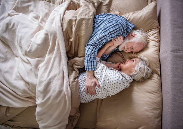 Calm pensioners embracing and lying in bed - Fotoğraf, Görsel