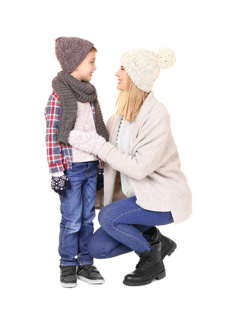 Cute little boy with mother in warm clothing on white background. Ready for winter vacation - Photo, image