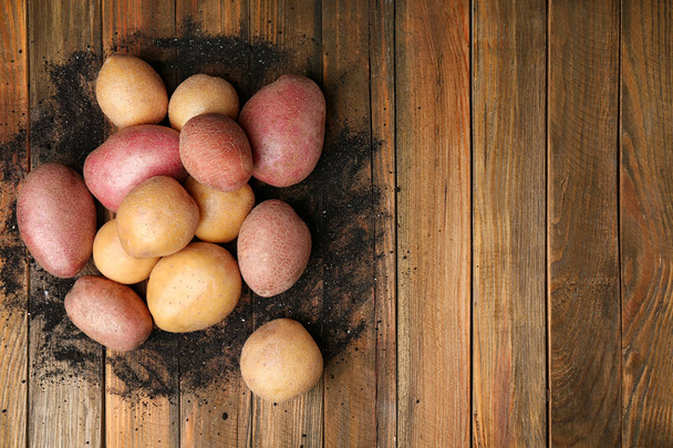 Fresh raw potatoes on wooden background, top view - Foto, afbeelding