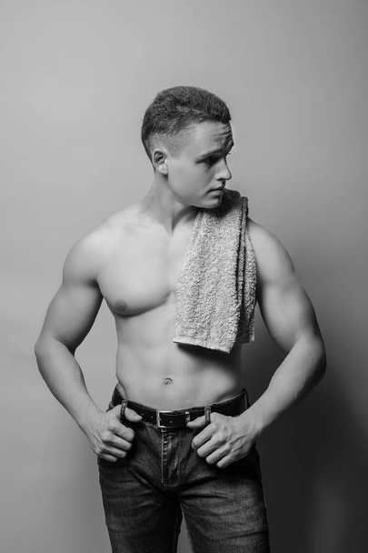 Portrait of muscular young bodybuilder on grey background, black and white effect - Foto, Imagen