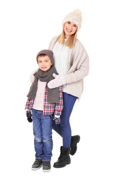 Mignon petit garçon avec mère en vêtements chauds sur fond blanc. Prêt pour les vacances d'hiver
 - Photo, image