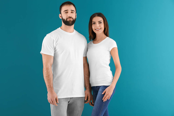 Jovem homem e mulher em elegantes camisetas brancas sobre fundo de cor. Mockup para design
 - Foto, Imagem