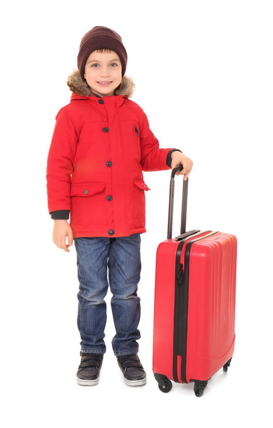 Cute little boy in warm clothing and luggage on white background. Ready for winter vacation - Fotó, kép
