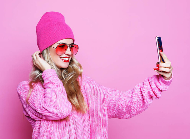 Fashion girl  taking photo makes self portrait on smartphone wea - Фото, изображение