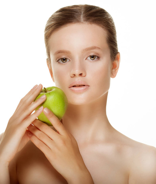 Head shot of woman holding green apple against white background - Foto, afbeelding