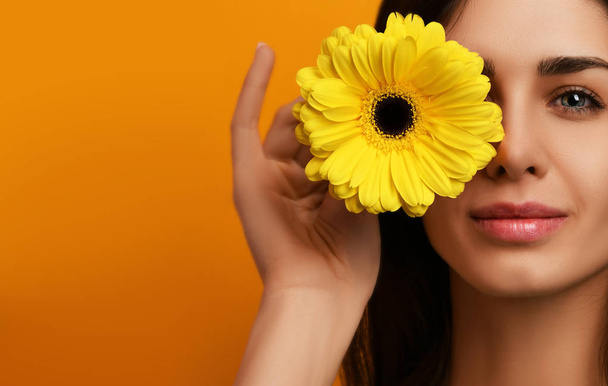 Young pretty woman hold yellow gerbera flower in green dress  - 写真・画像