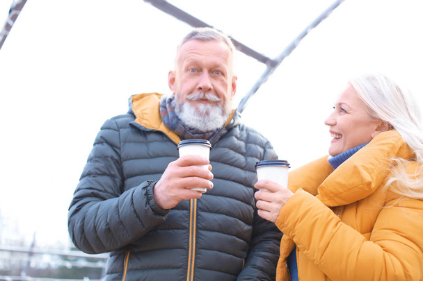 Happy mature couple with coffee outdoors - Foto, imagen