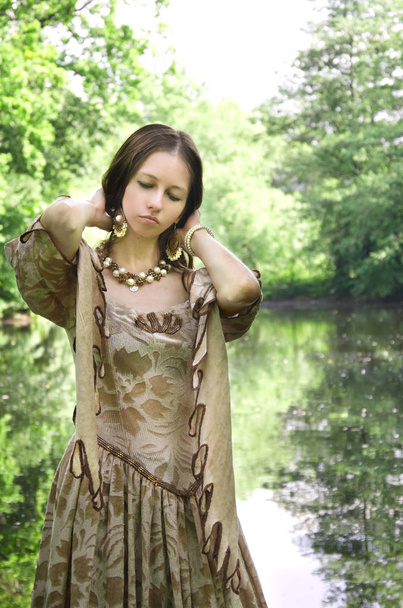 mladá žena v vintage drží hlavu na břehu rybníka - Fotografie, Obrázek