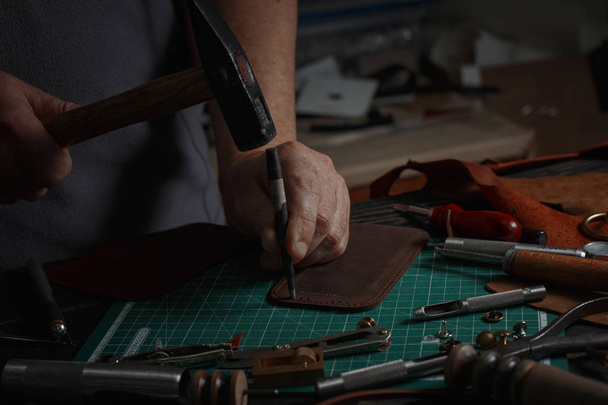 Mies työskentelee nahkaa käyttäen käsityökaluja DIY työkaluja
 - Valokuva, kuva