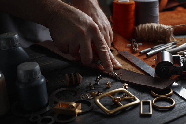 Mann bearbeitet Leder mit Bastelwerkzeugen - Foto, Bild