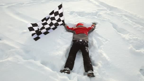 Ο άνθρωπος κείτεται στο χιόνι με τη σημαία του τερματισμού - Πλάνα, βίντεο