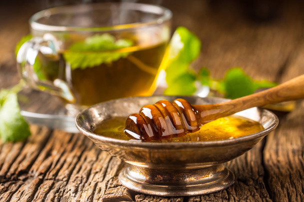 Honey. Honey and honey dipper on rustic oak table. Hot herb tea in the background - Φωτογραφία, εικόνα