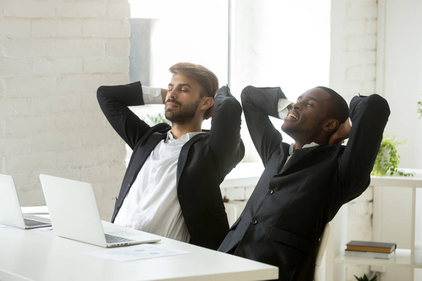 Two diverse young businessmen relaxing at work breathing fresh a - Foto, Imagem