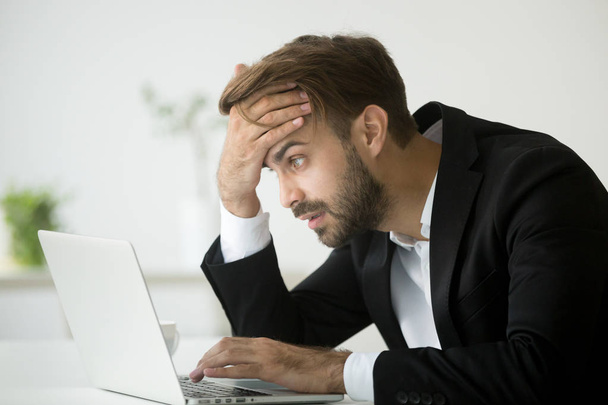 Worried stressed businessman shocked by bad news online using la - Фото, изображение