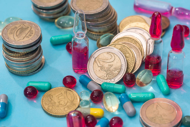 Euro coin with pills isolated on blue background - 写真・画像