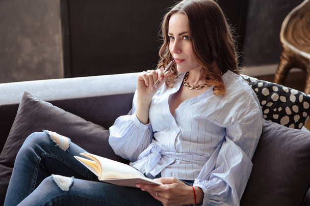Beautiful young woman with schedule notebook in stylish home interior. Freelancer business lady in her working place. - Fotoğraf, Görsel