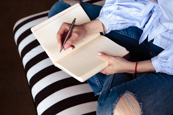 Close-up foto van planner notitieblok op een houten tafel. Vrouwelijke hand schrijft op papier. Plat lag samenstelling. - Foto, afbeelding