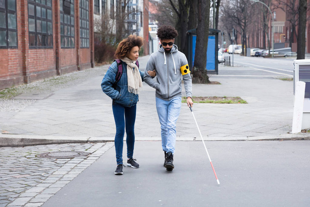 Young Woman Helping Blind Man With White Stick While Crossing Road - Valokuva, kuva