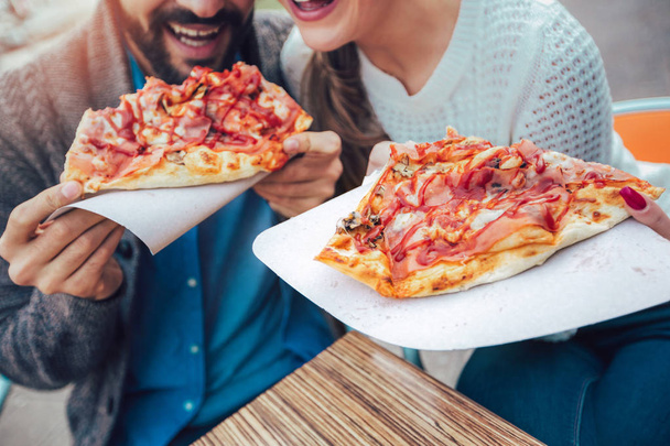 Couple eating pizza outdoors in a outdoor cafe, close up. - Zdjęcie, obraz