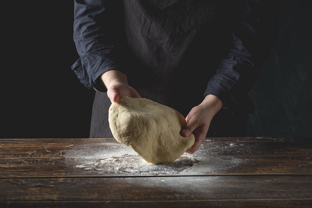chefhands preparing dough over wooden background, top view - 写真・画像