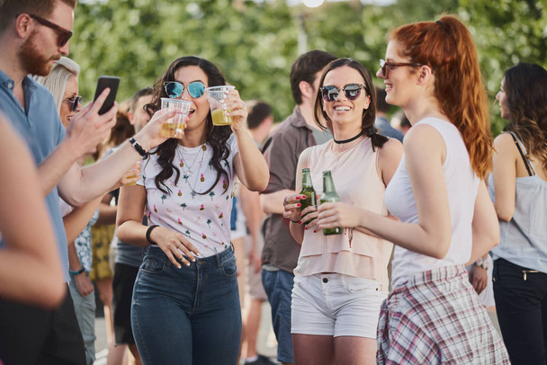 Group of people standing and drinking at the summer outdoor party  - Photo, Image