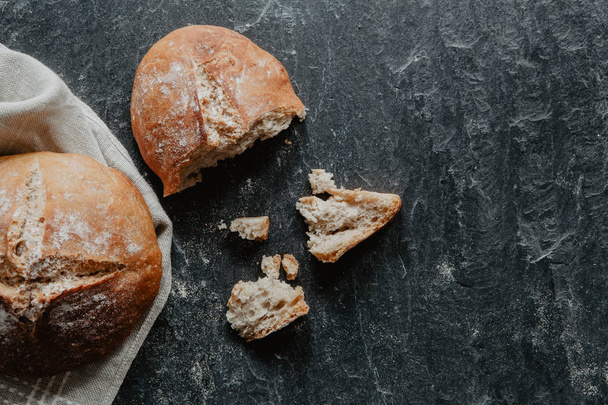 Freshly baked bread on black stone - 写真・画像