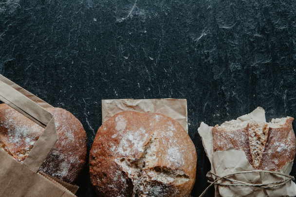 Homemade loaf of bread on the bottom of stone background - 写真・画像