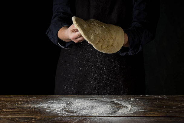 close up of male chef hands preparing dough over wooden background - Zdjęcie, obraz