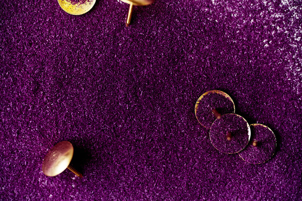  golden pushpins in violet powder with grainy texture, close-up  - 写真・画像
