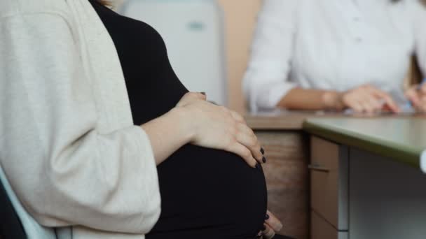 The pregnant patient will learn the results of the tests from her doctor. A woman doctor gives advice on preparing for childbirth. The doctors office is in the hospital. Happy mother. Child in the - Πλάνα, βίντεο