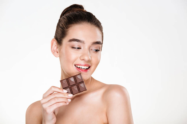 Portrait of fresh cute female model with dark hair eating chocol - Photo, Image