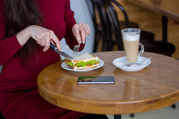 Chica en la mesa se corta un sándwich en un almuerzo de negocios, primer plano
. - Foto, Imagen