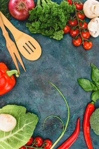 top view of fresh healthy vegetables and wooden utensils on black - Foto, imagen