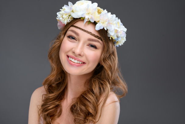 close-up portrait of happy young woman with curly hair in white floral wreath isolated on grey - Photo, image