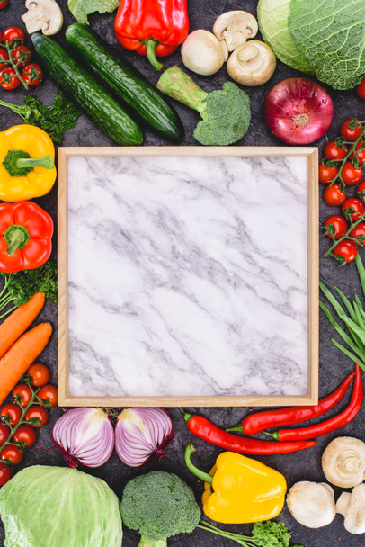 vista superior de verduras frescas crudas y tablero de mármol en blanco sobre negro
 - Foto, Imagen