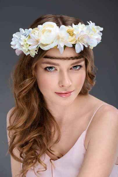 beautiful young woman with curly hair in floral wreath isolated on grey - Foto, immagini