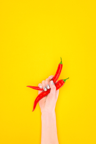 cropped shot of person holding red chili peppers isolated on yellow - Photo, Image