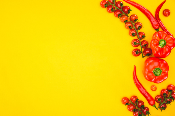 το Top view φρέσκα ωμά πιπεριές και ντοματίνια που απομονώνονται σε κίτρινο  - Φωτογραφία, εικόνα