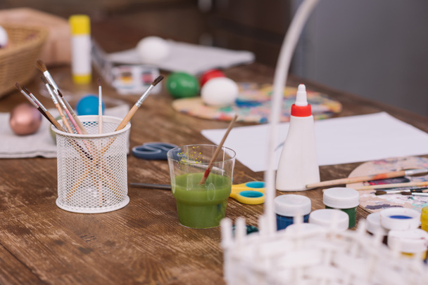 paint brushes and poster paints for easter eggs on wooden table - 写真・画像