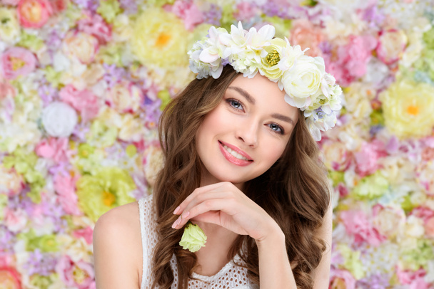 Улыбающаяся молодая женщина в цветочном венке с цветущим бутоном розы
 - Фото, изображение