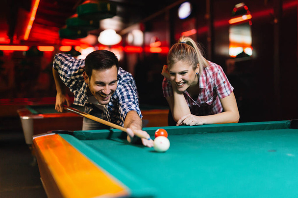 Young attractive couple playing snooker together in bar - Photo, Image