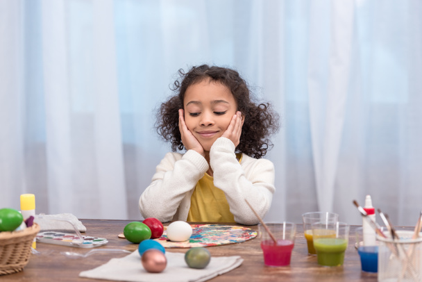 african american kid resting chin on hands and looking at painted easter eggs - Foto, Bild