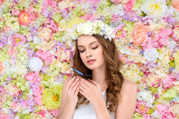 jeune femme aux cheveux bouclés en couronne florale avec papillon à portée de main
 - Photo, image