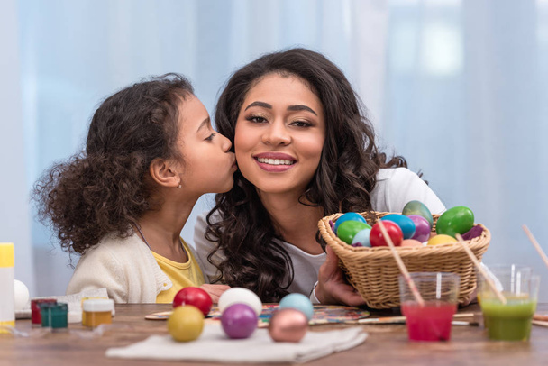african american daughter kissing happy mother near painted easter eggs - Foto, Imagen